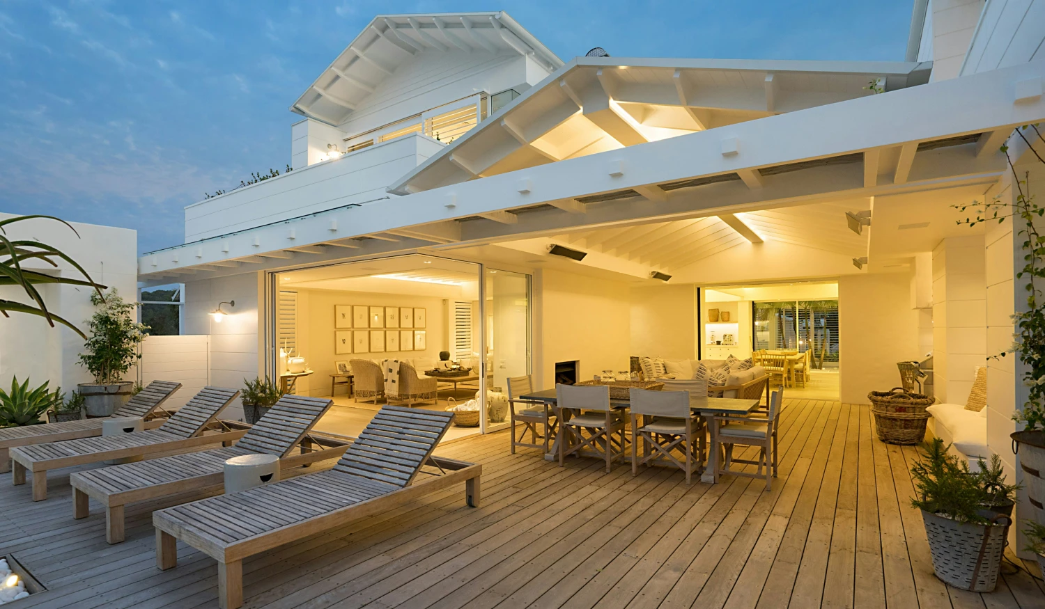 A white house with a wooden deck at dusk.